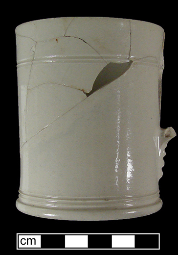 Mug with incised lathe turned decoration at base and rim. Handle terminal notched faceting detail &ndash; used by a number of Staffordshire potteries (Hilyard 2005 p. 41, 44).  Recovered from a well filled c. 1720s - c. 1750s, (Lots 2341, 2343).